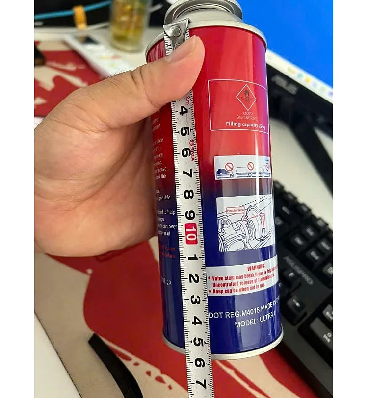 Tay cầm lon gas mini đỏ xanh cạnh thước dây đo chiều cao lon